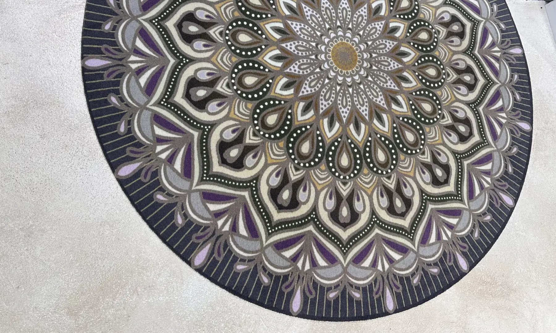 Ronde schoonloopmat met mandala-print in paars en grijs op een betonvloer